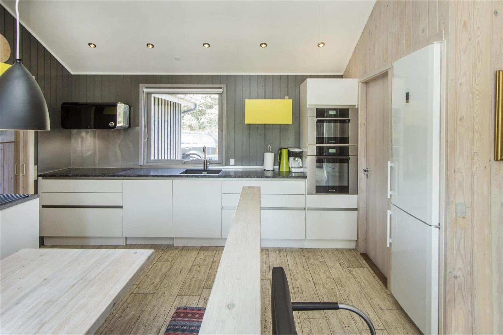 Moderne Küche mit weißen Schränken, Kühlschrank und Fenster.
