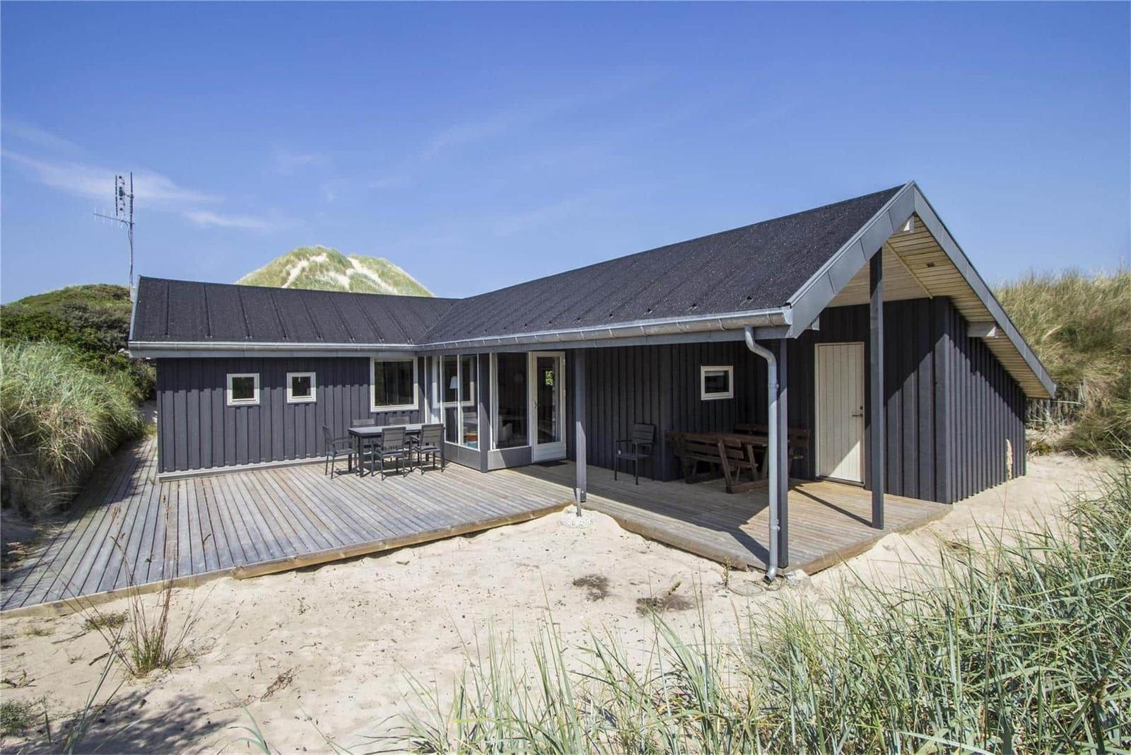 Modernes Ferienhaus mit Terrasse, Gartenmöbeln und Strandnähe.