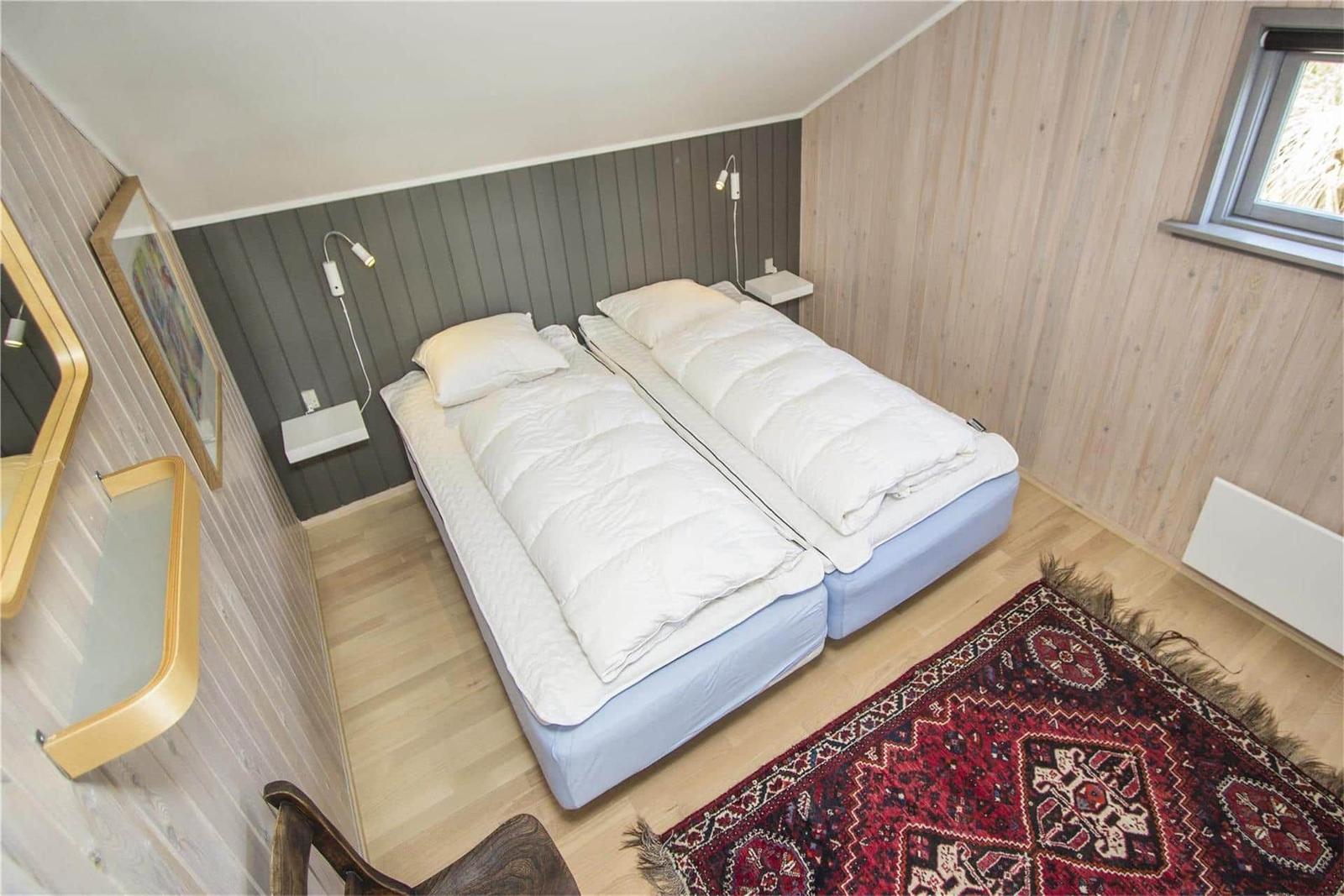 Zwei Betten mit weißen Bettwäschen stehen in einem Raum mit Holzwänden und einem roten Teppich.