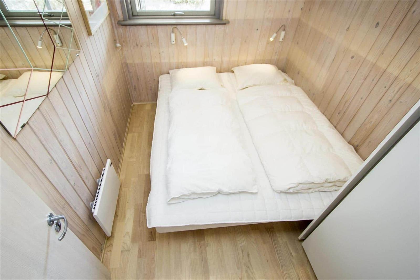 Schlafzimmer mit Bett, Holzwand und Fenster