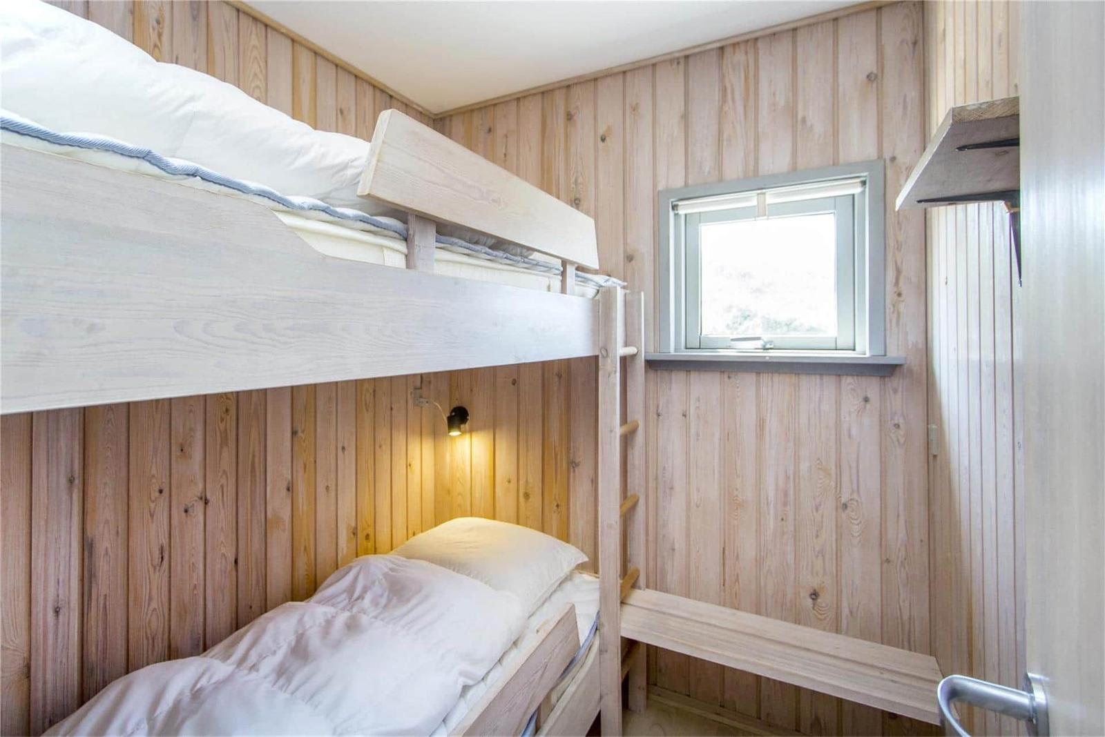 Zimmer mit Doppelstockbett, Holzwand und Fenster.