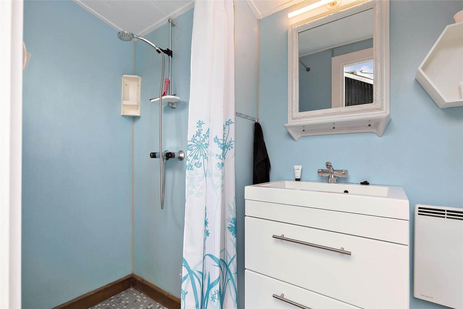 Badezimmer mit Dusche, Waschbecken und Spiegel.
