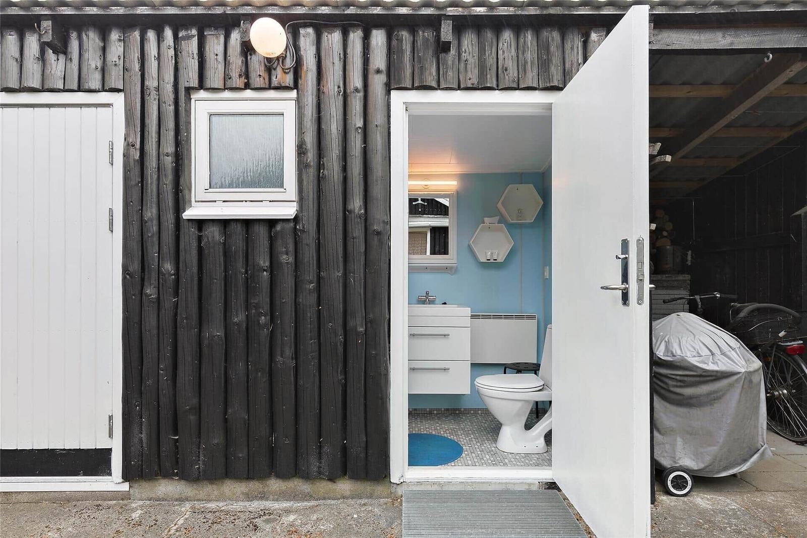 Badezimmer mit Toilette und Waschbecken, blaue Wände, weißes Mobiliar.