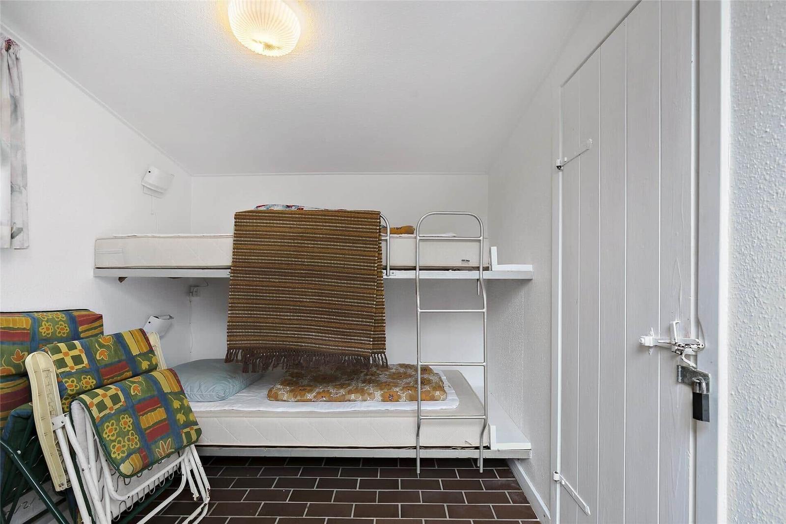 Zimmer mit Doppelbett und Schlafcouch, brauner Fliesenboden und weißer Tür mit Schloss.