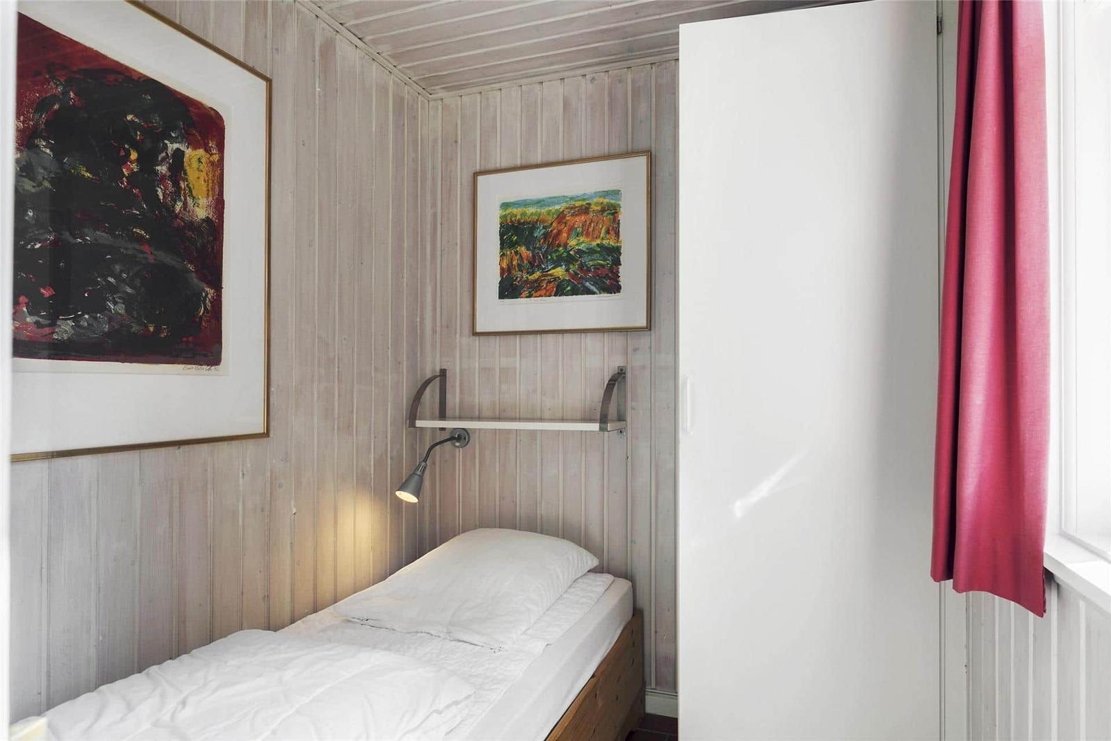 Ein Schlafzimmer mit Bett, Wandbildern und einem weißen Schrank.