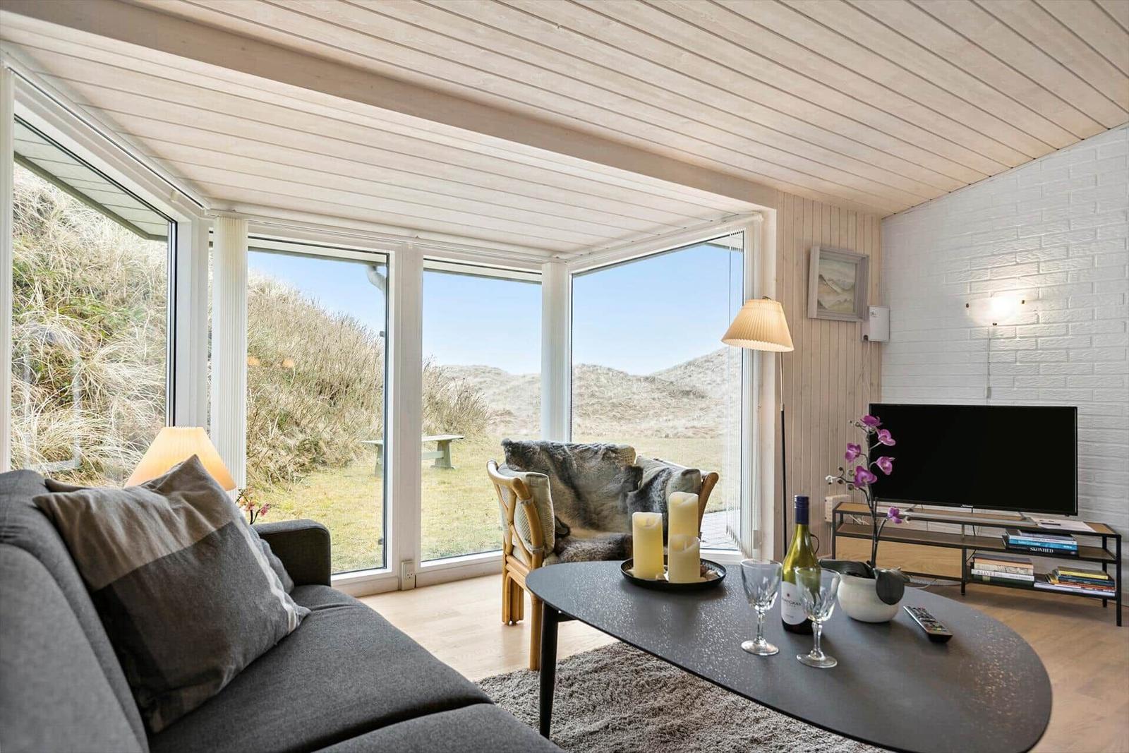 Living room with large windows, sofa, coffee table, and TV.