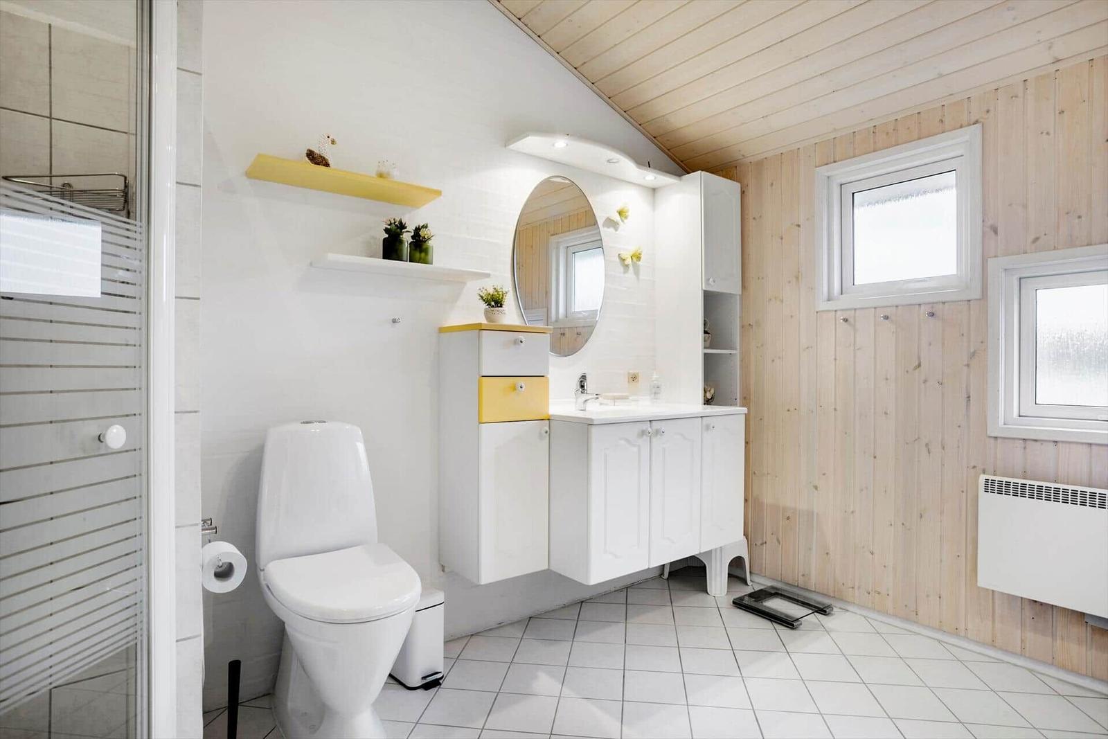 Bathroom with shower, toilet, and sink. Wooden wall, windows, and radiator.
