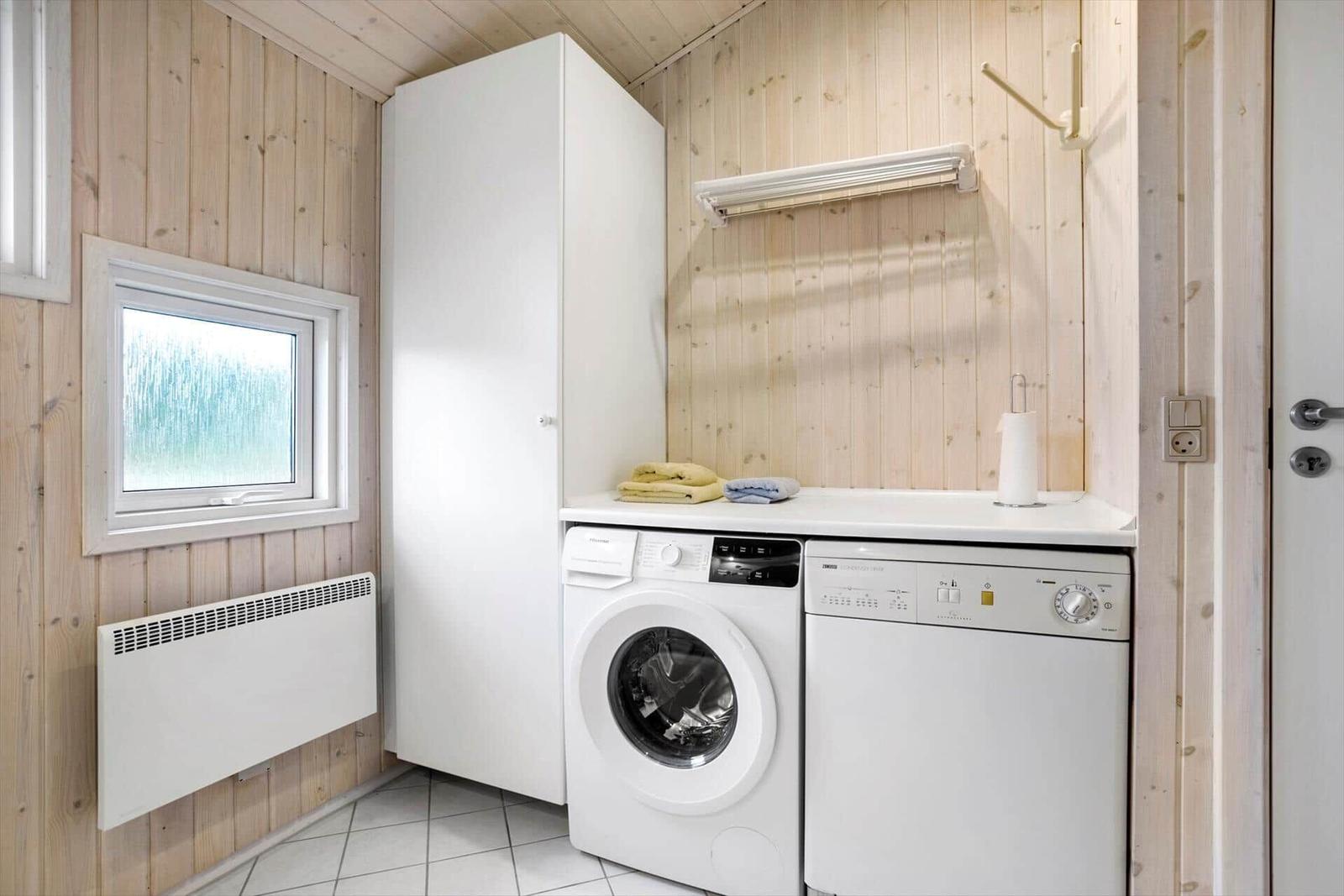 Washing machine and dishwasher in a room with wooden walls and window.