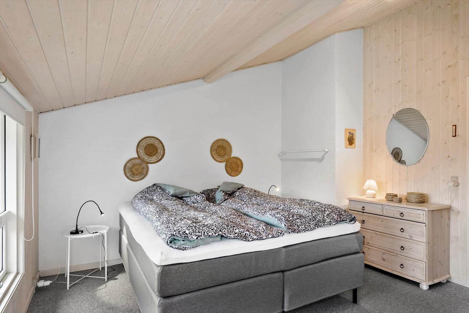Bedroom with double bed, dresser, and wall decor.