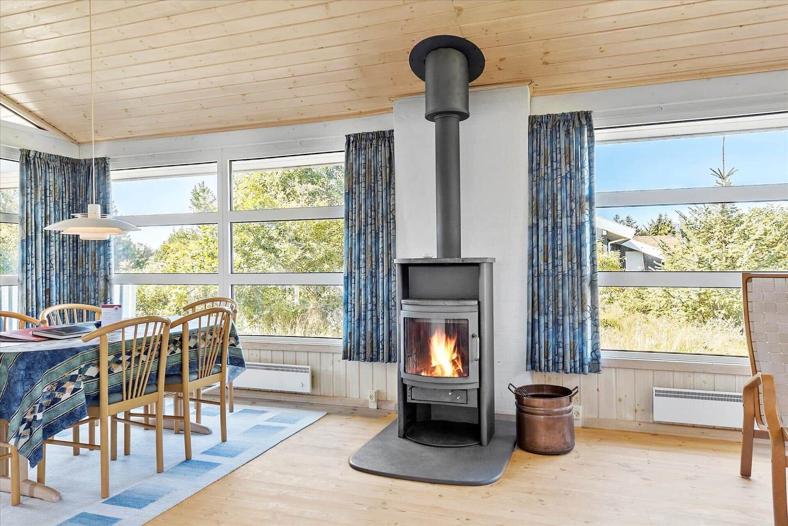Room with fireplace, dining table, and large windows with nature view.