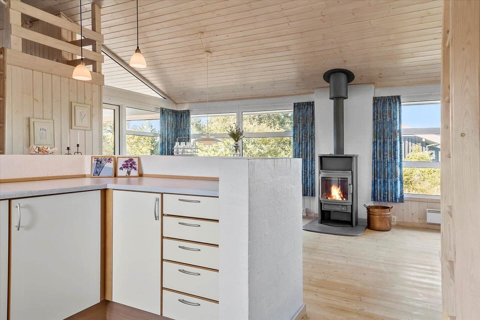 Kitchen with wooden ceiling, fireplace, and large windows.