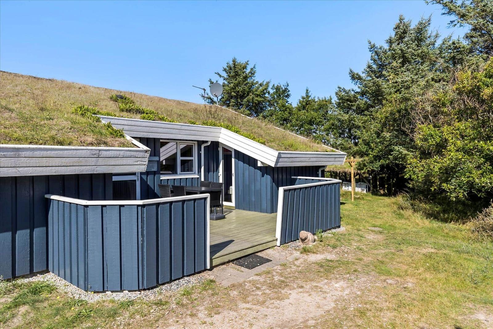 A house with a green roof, terrace, and garden. A satellite dish is mounted.