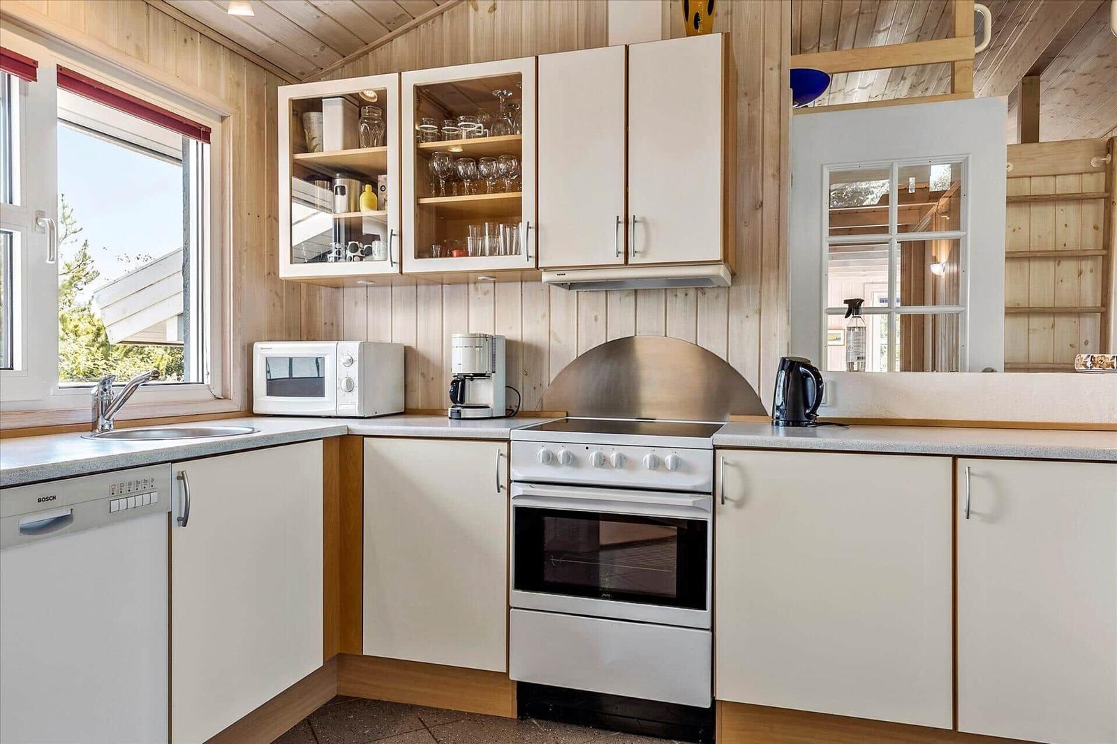 Kitchen with white cabinets, stove, and window.
