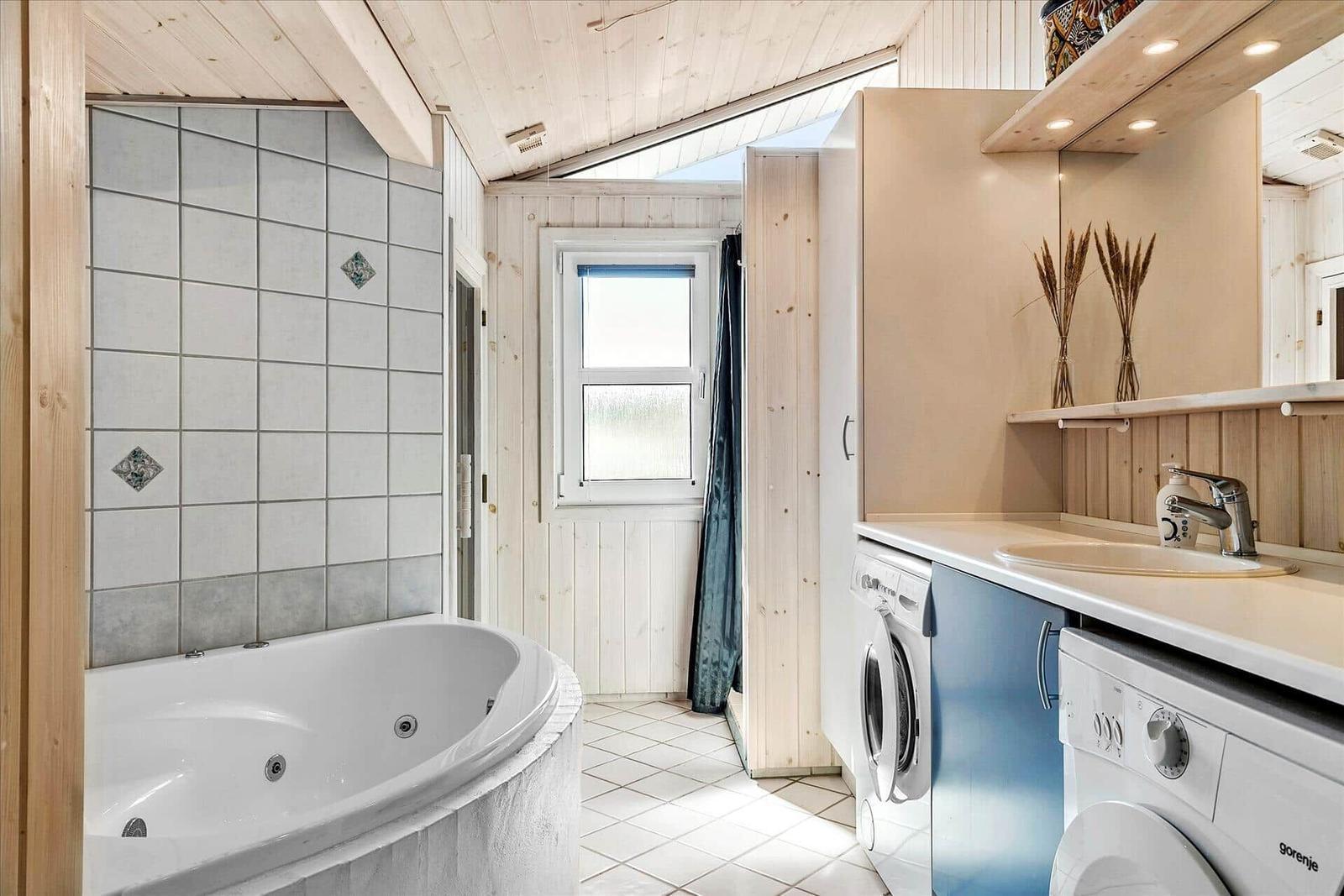 Bathroom with whirlpool, washing machine, and sink under wooden ceiling.