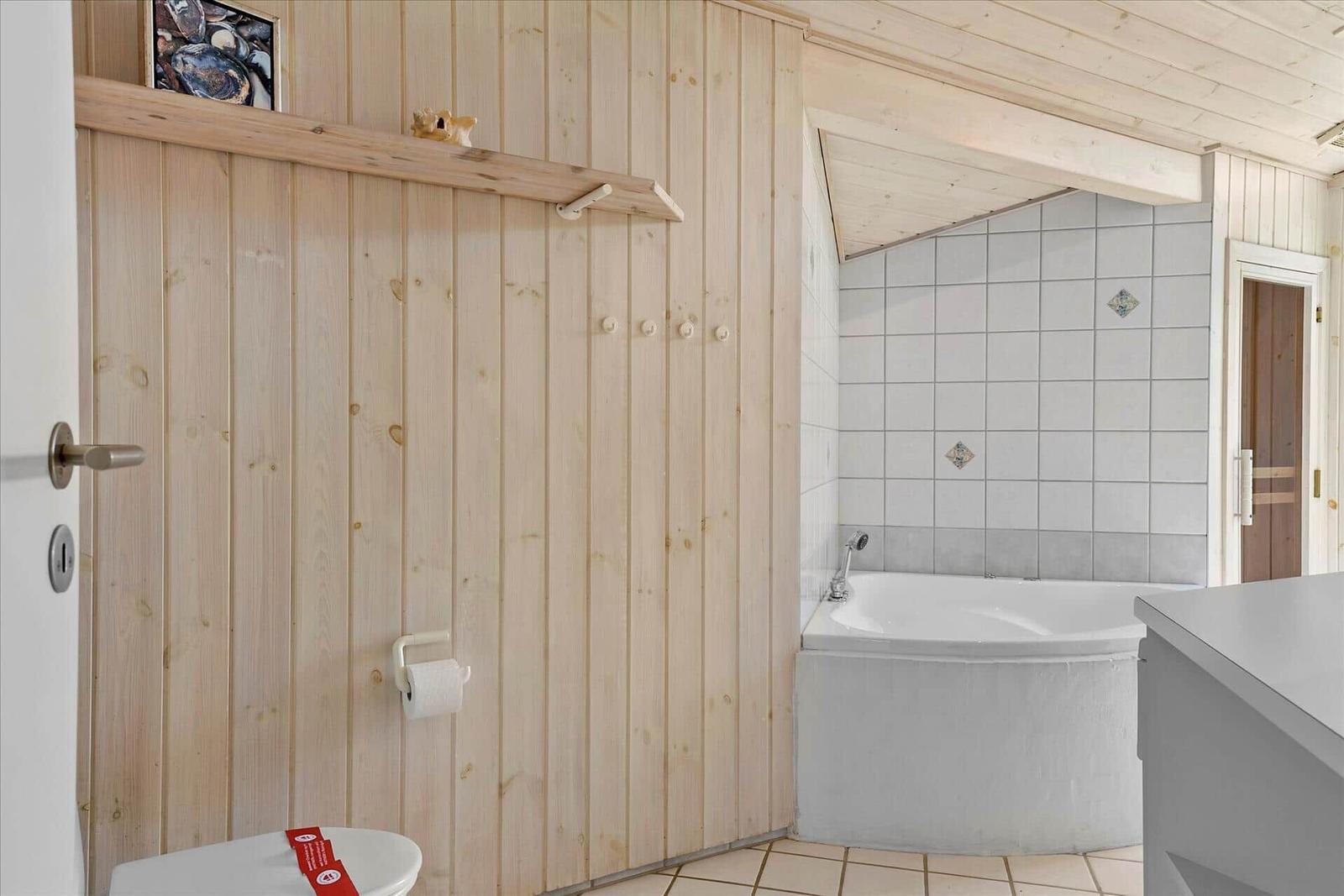Bathroom with bathtub, wooden wall, and toilet.