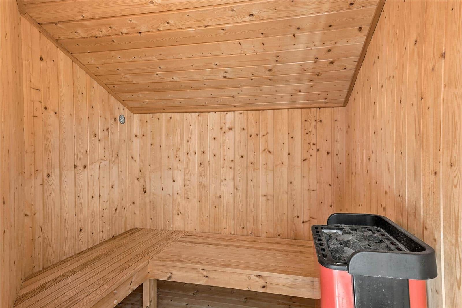 Sauna with wooden walls, bench, and heater with stones.