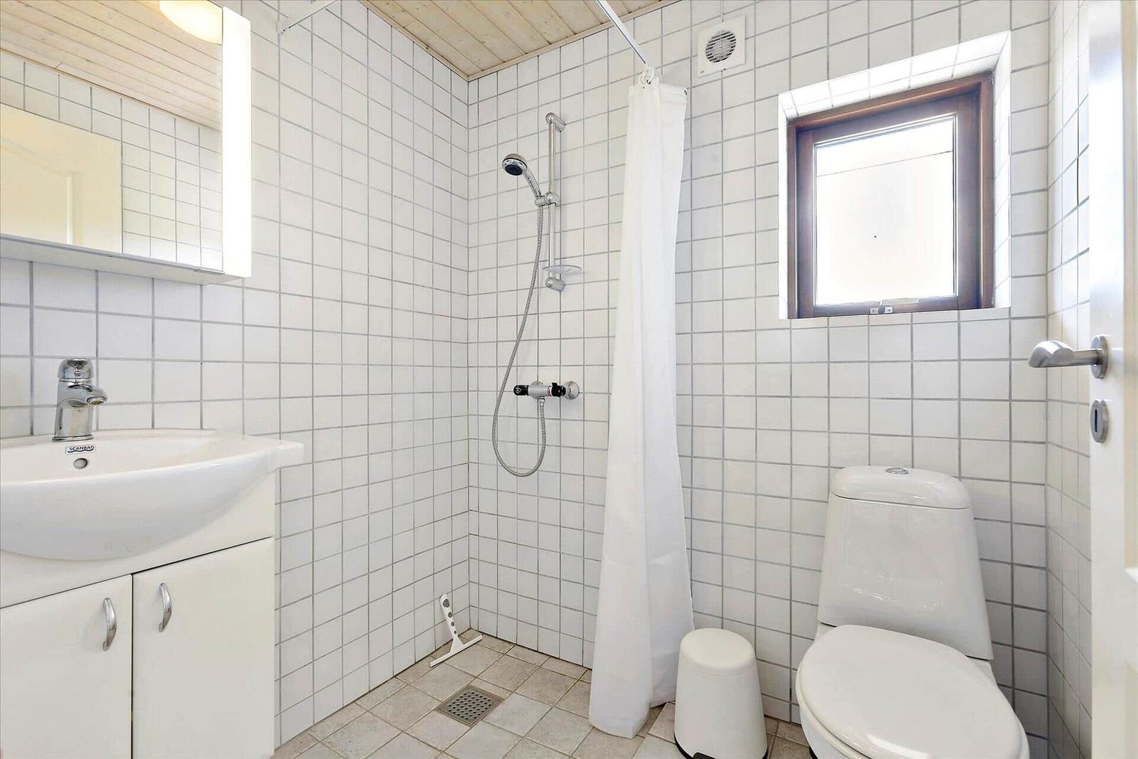 Badezimmer mit Dusche, Toilette und Waschbecken mit Spiegel.