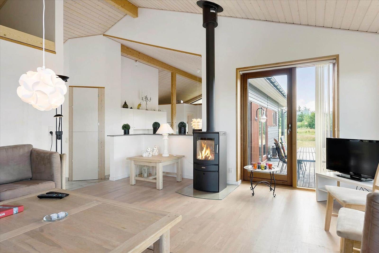 Wohnraum mit Kamin, Sofa, Esstisch und Blick auf Terrasse.