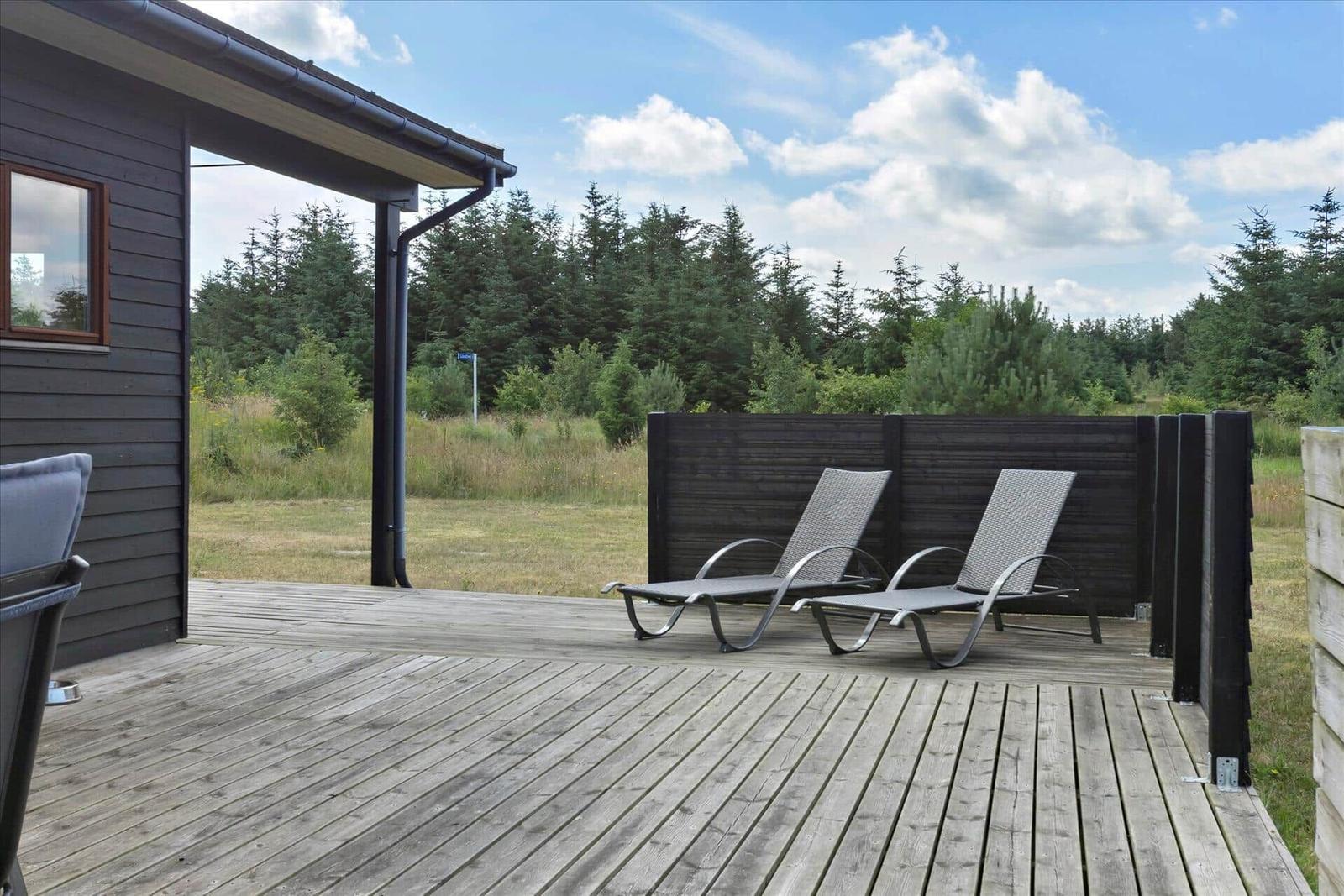 Terrasse mit zwei Liegestühlen und Blick auf Wald.