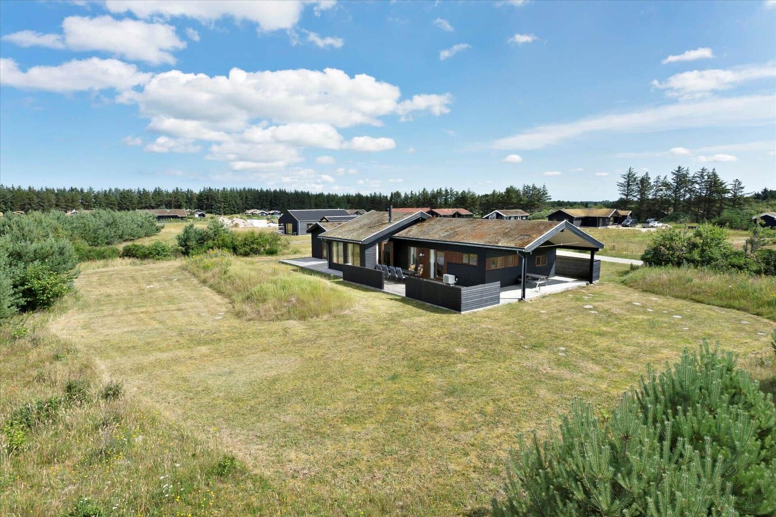 Moderne Ferienhaus mit Terrasse und Garten. Blick auf Wald und Himmel.