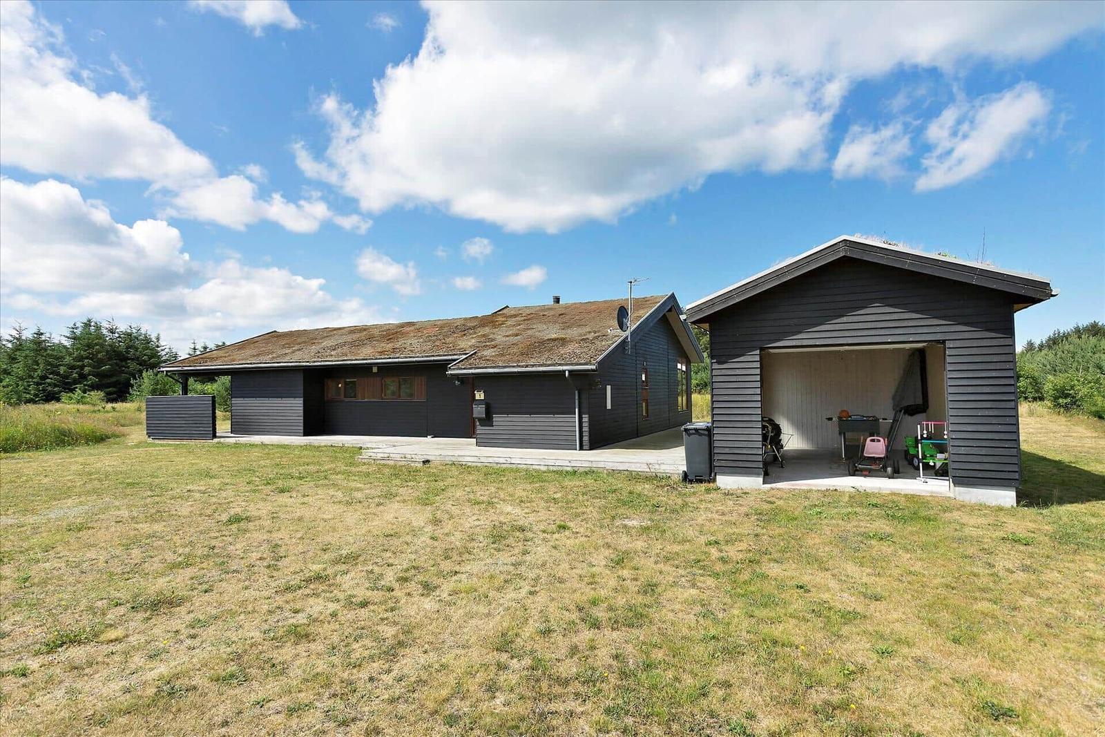 Moderne Villa mit Garage und Rasenfläche unter blauem Himmel.