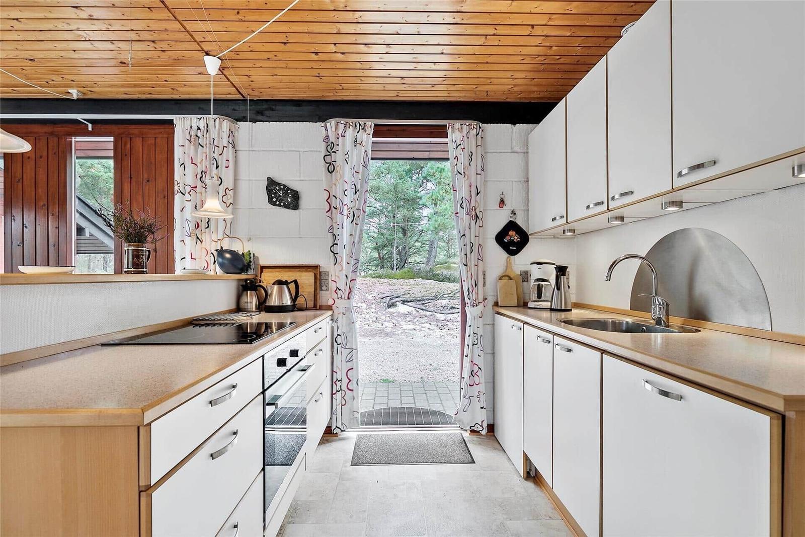 Küche mit weißen Schränken und Holzoberflächen, Blick auf Außenbereich.