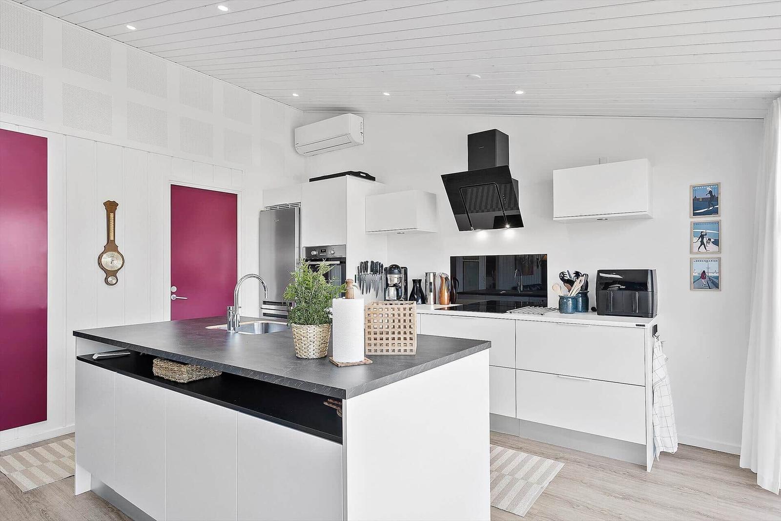 Moderne Küche mit weißer Einbauküche, dunklem Arbeitsplatz und pinken Türen.