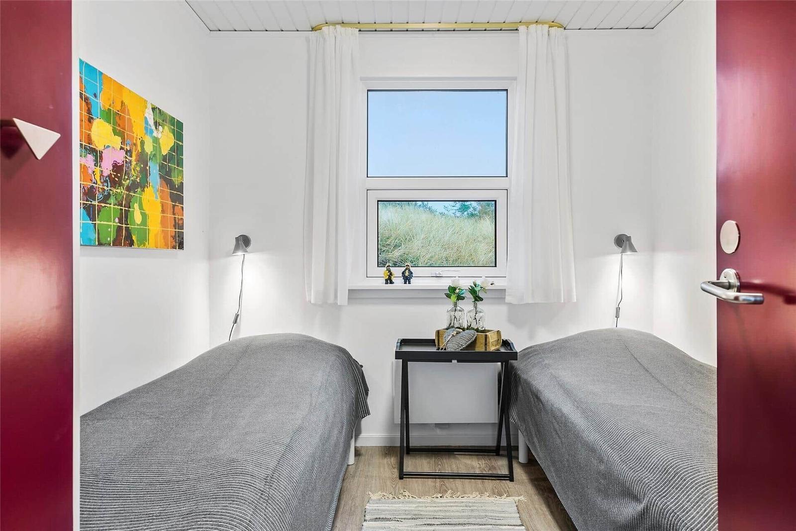 Zwei Betten, Fenster mit Blick auf Gras, Tisch mit Vasen und Wandbild.