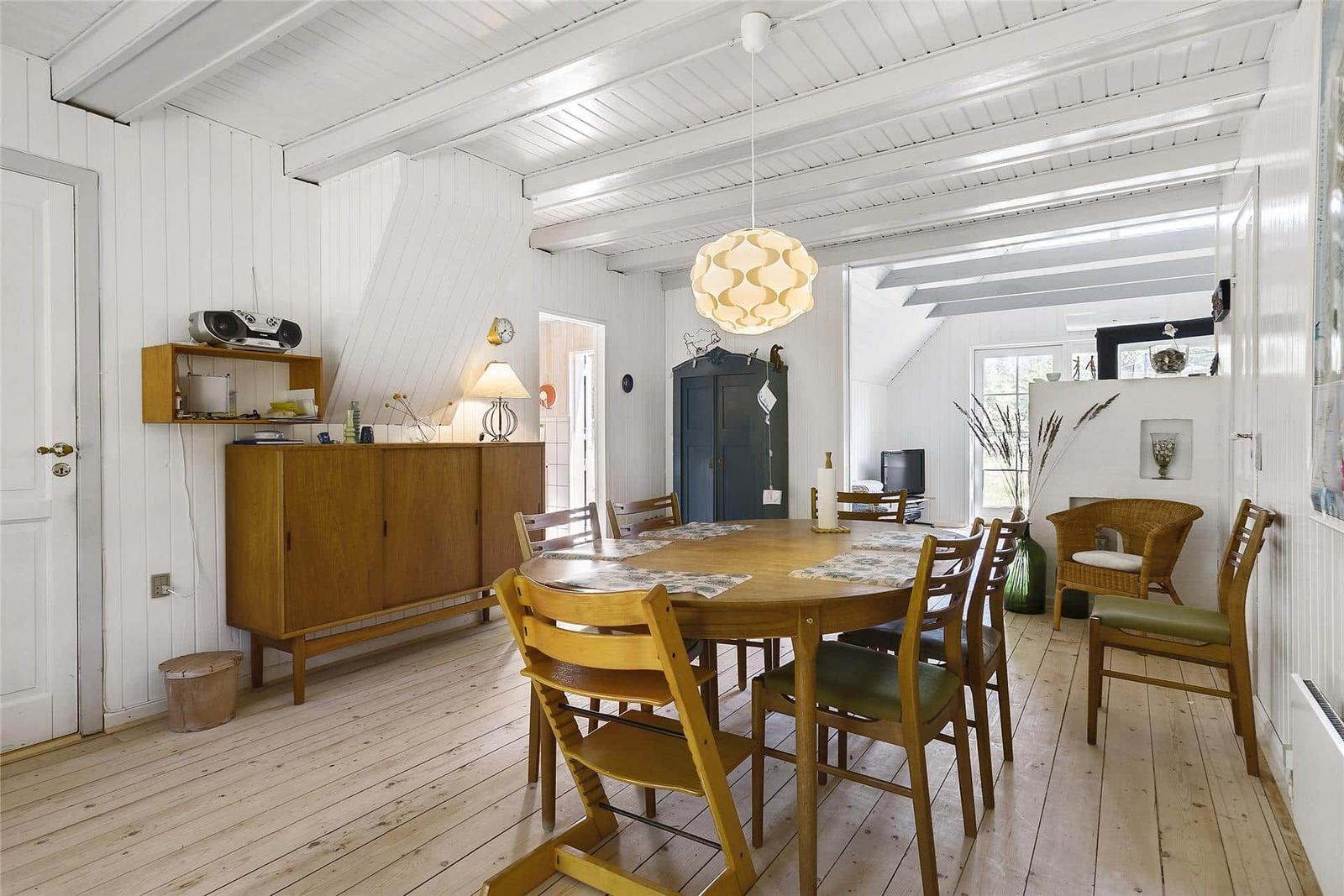 Esszimmer mit Holztisch, Stühlen und weißen Wänden.