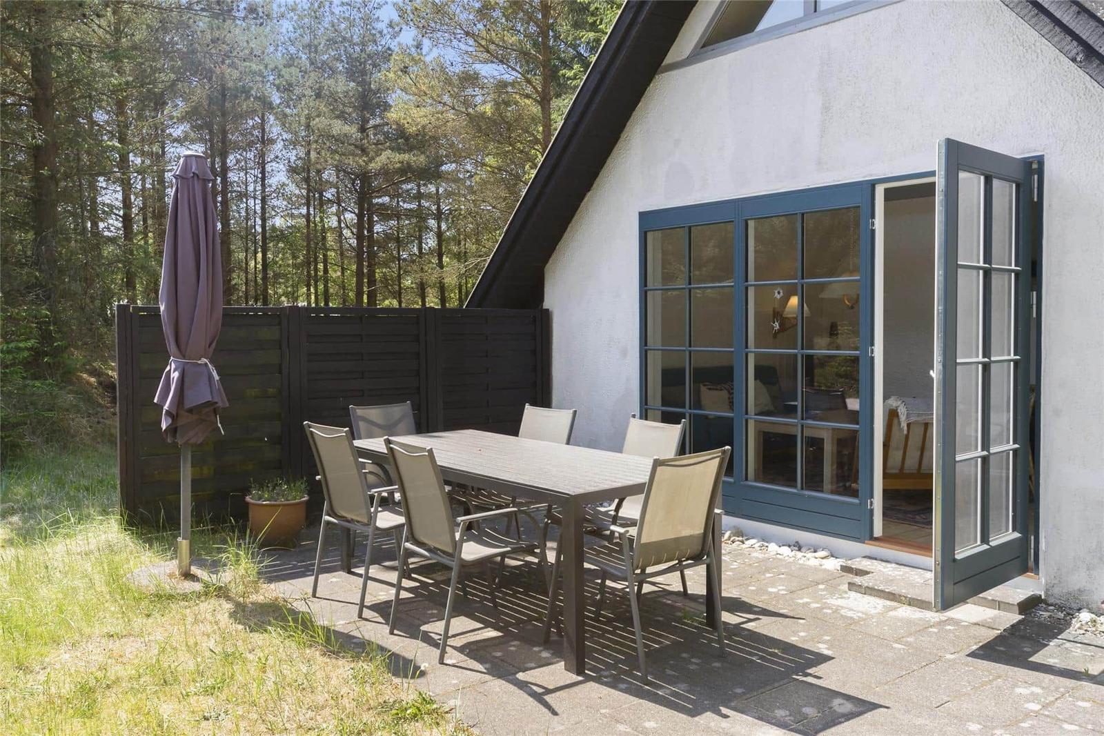Terrasse mit Tisch und Stühlen neben einem Haus mit Glastüren.