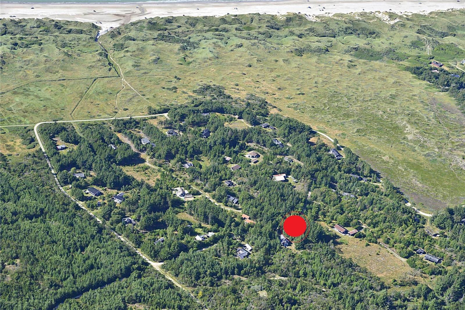Luftbild einer Waldlandschaft mit markierter Immobilienposition und Strand im Hintergrund.