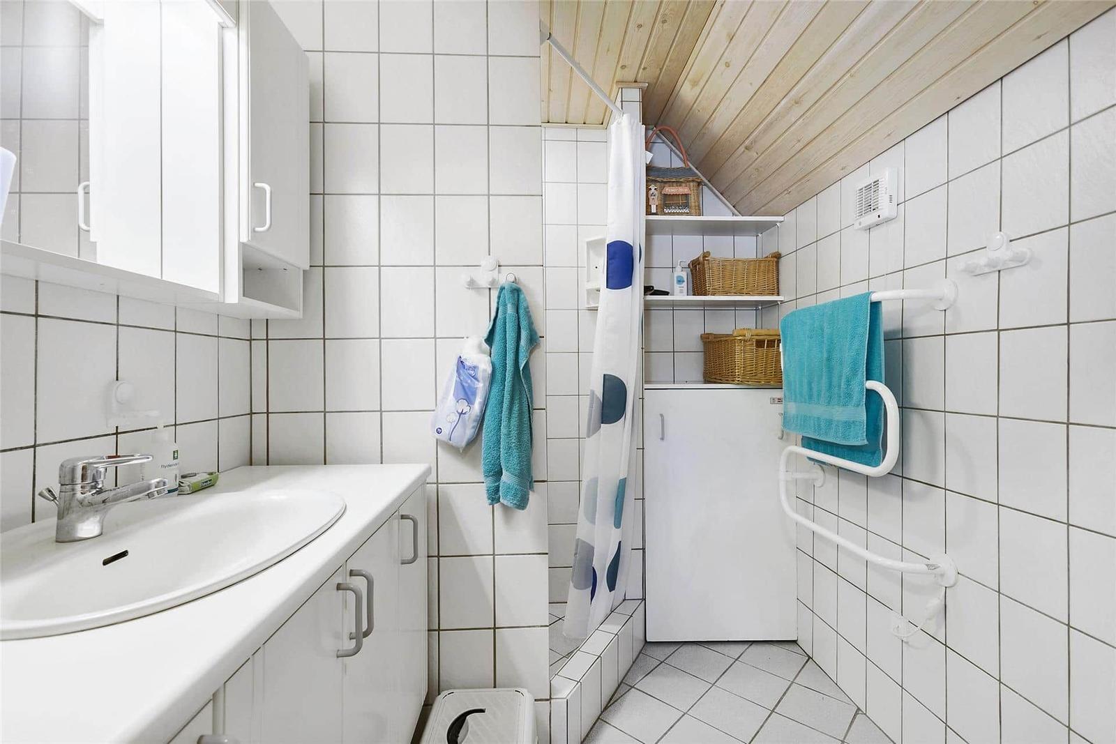 Badezimmer mit Dusche, Waschbecken und Handtuchhalter.