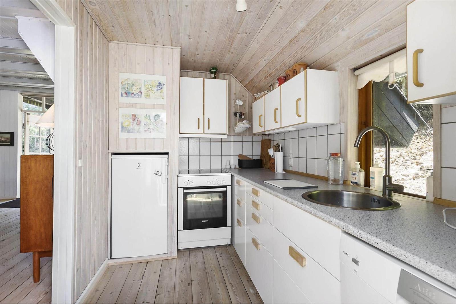 Küche mit weißen Schränken, Arbeitsplatte und Fenster