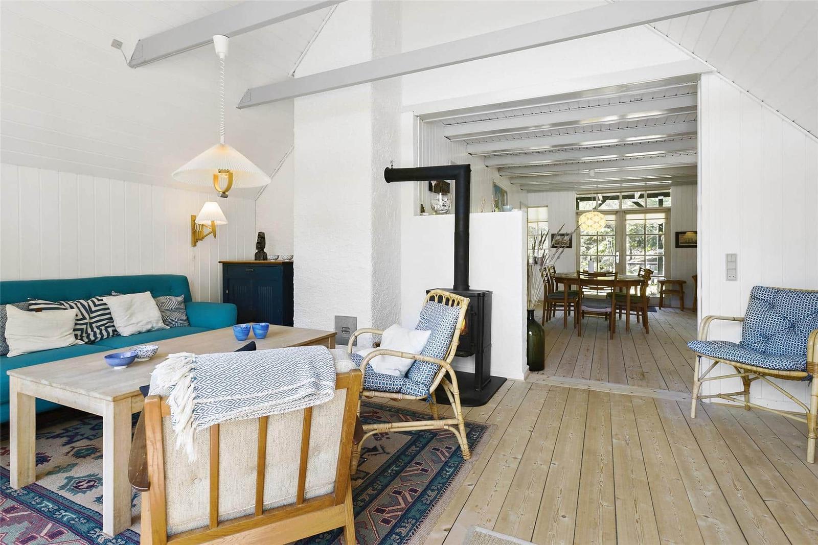 Wohnbereich mit Sofa, Sitzgelegenheiten und Kamin. Holzboden und weiße Wände.