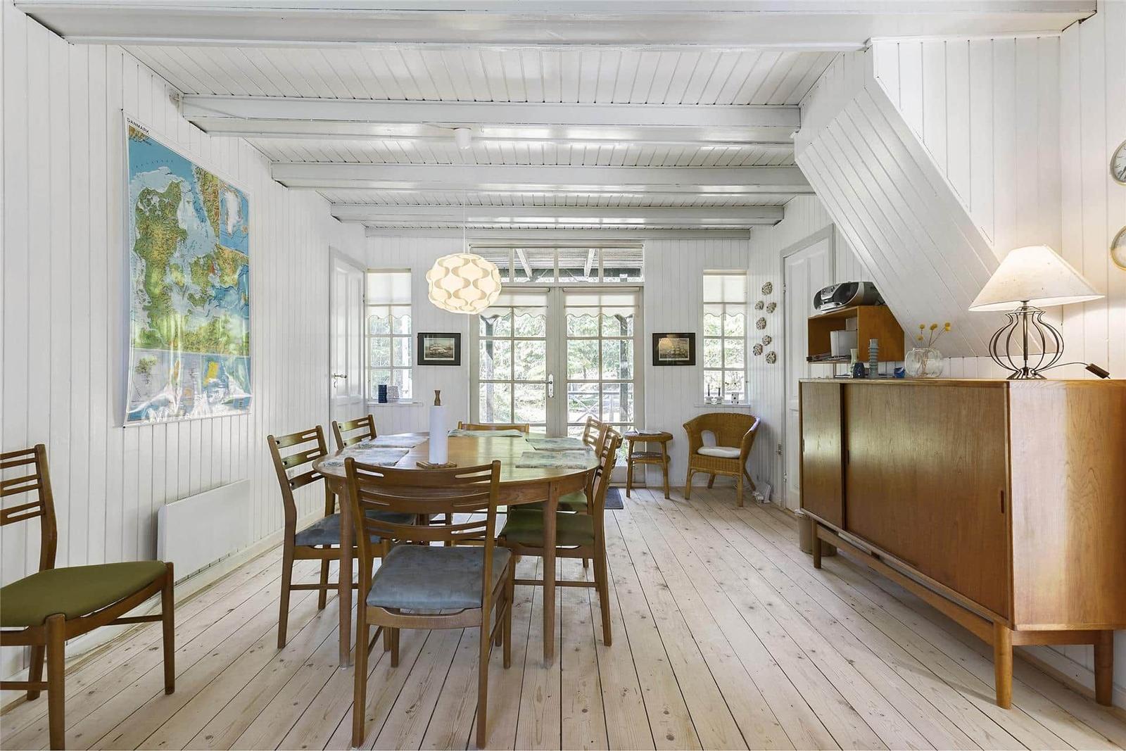 Esszimmer mit Holzboden, Tisch, Stühle und Kamin. Wandkarte und Holzschrank sichtbar.