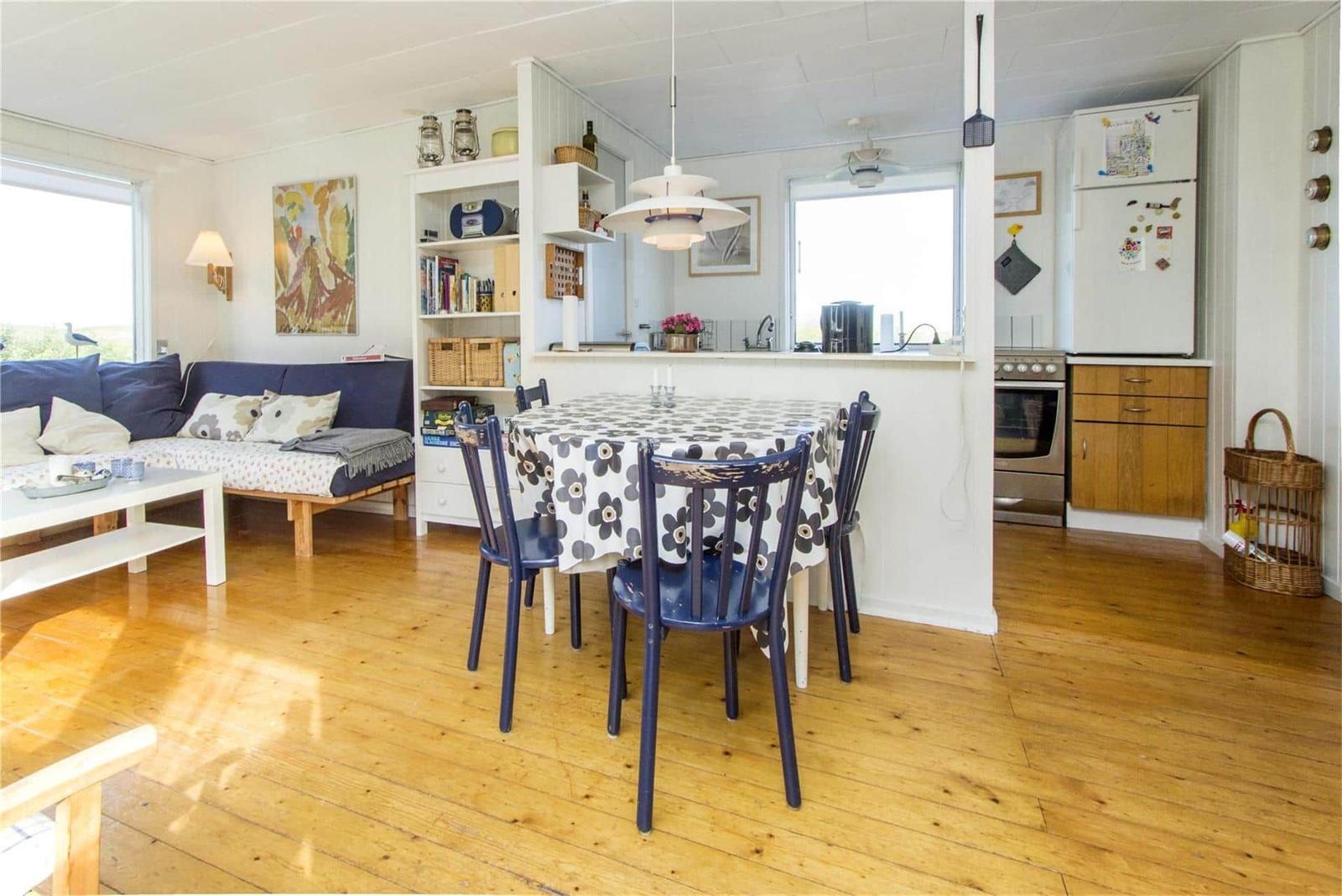 Living room with dining table, sofa, and kitchen in background.