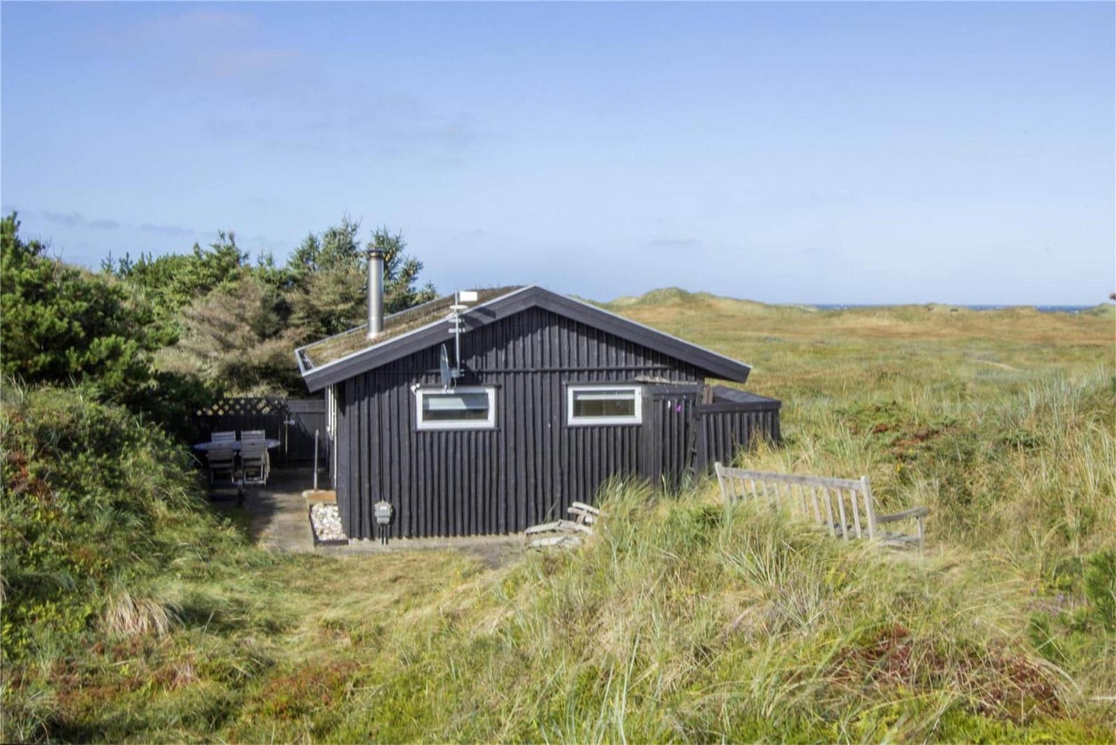 Black cabin with terrace and garden in dune landscape