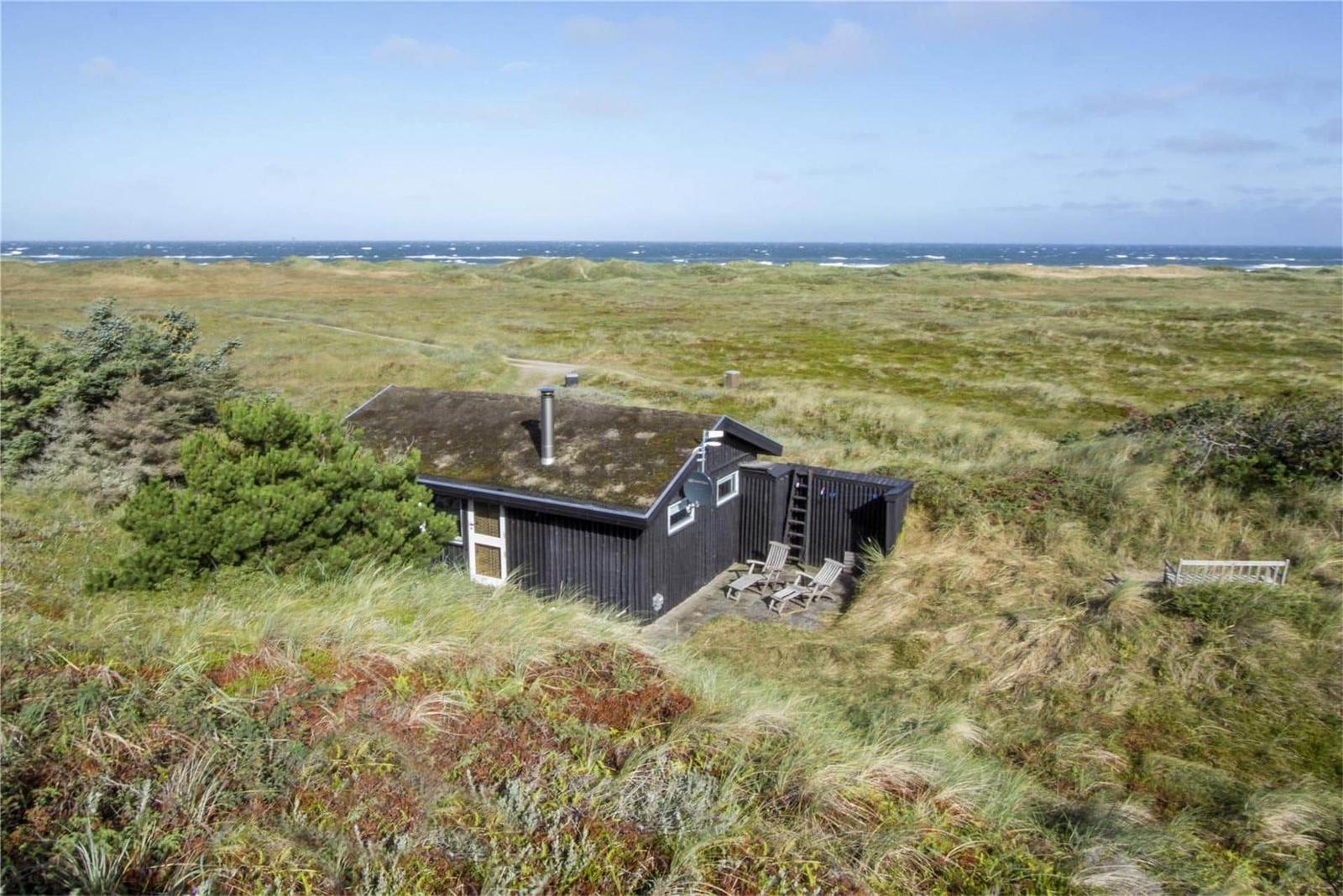 Wooden house with terrace in dunes, view of the sea.