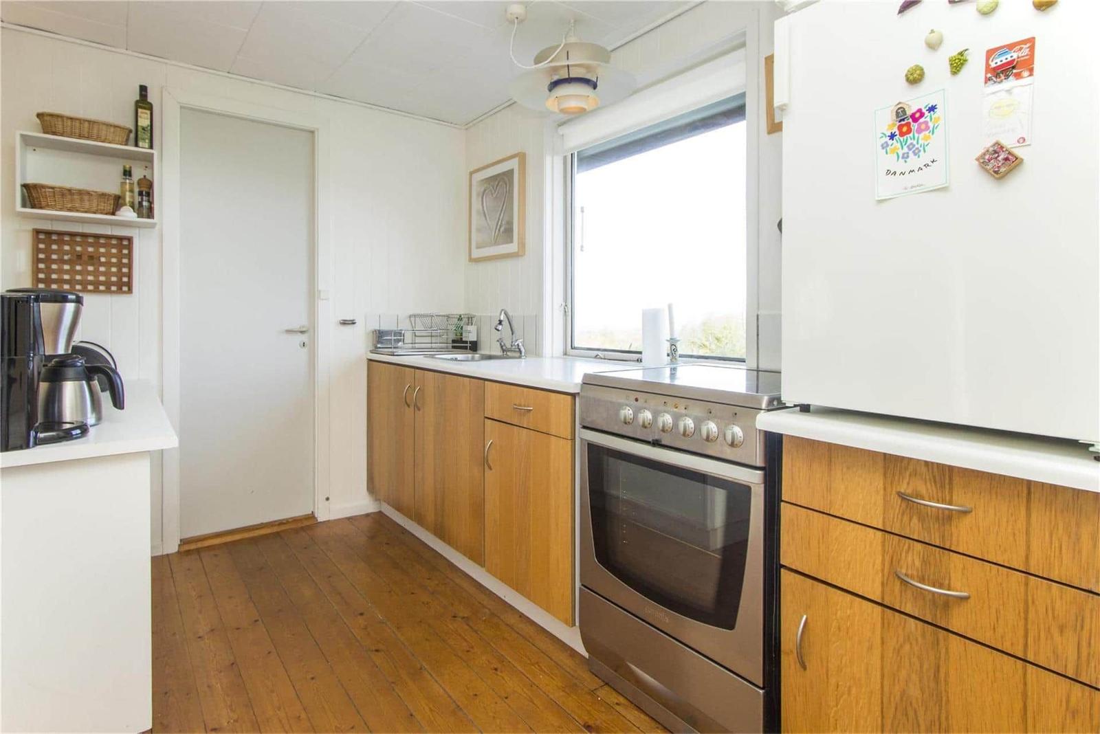 Kitchen with wooden cabinets, stainless steel stove, and refrigerator with magnets.