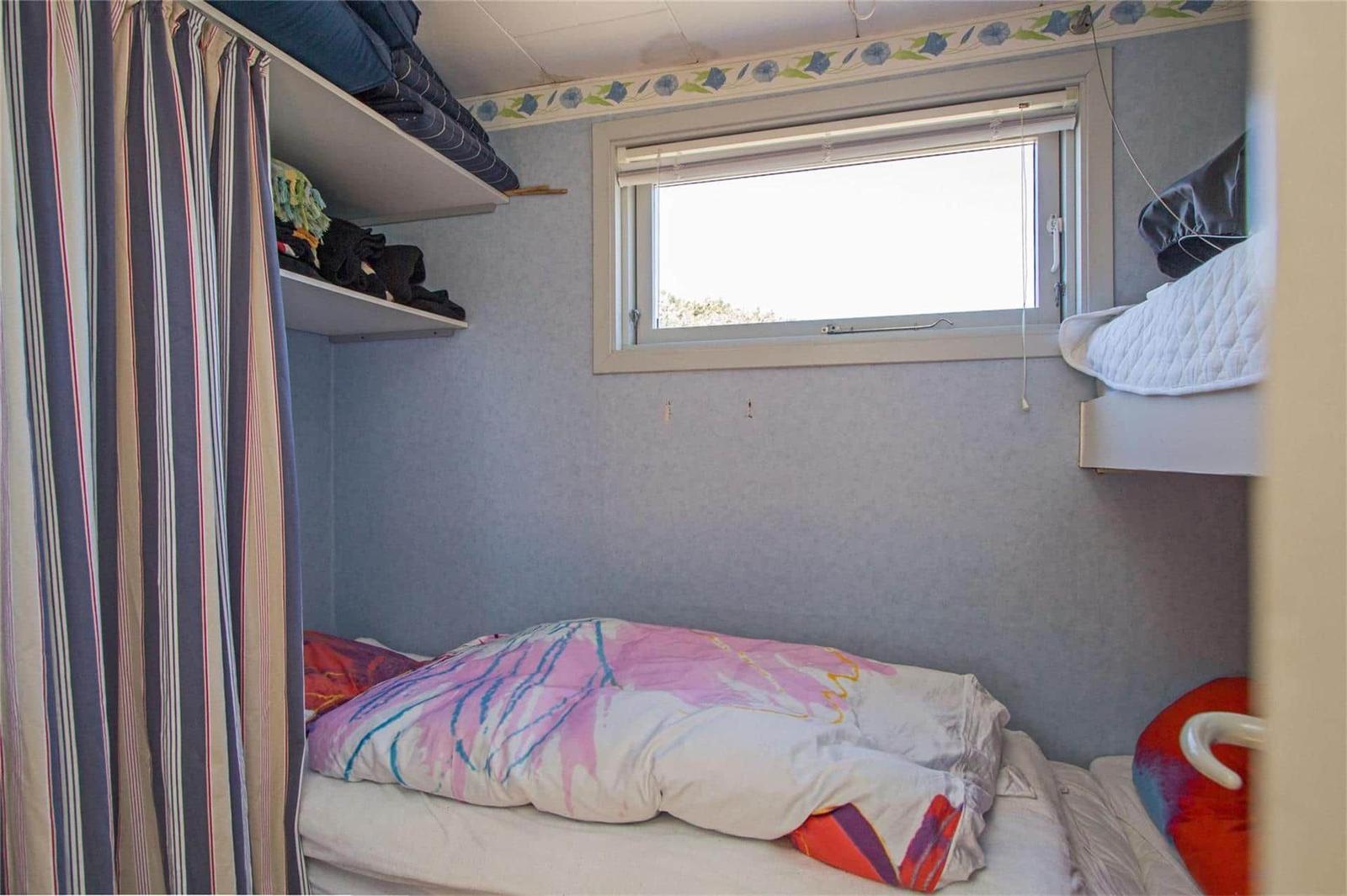 Small bedroom with double bed, window, and shelves.