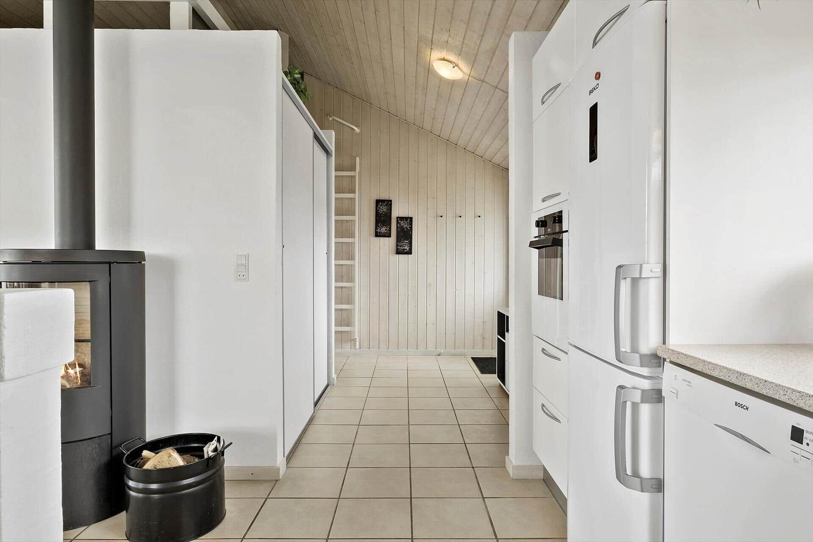 Küche mit weißen Geräten und Holzwand im Hintergrund.