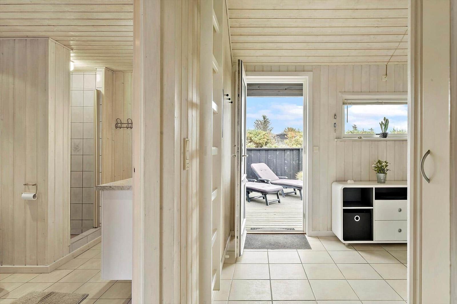 Helle Flure mit Holzwand und Terrasse mit Liegen.