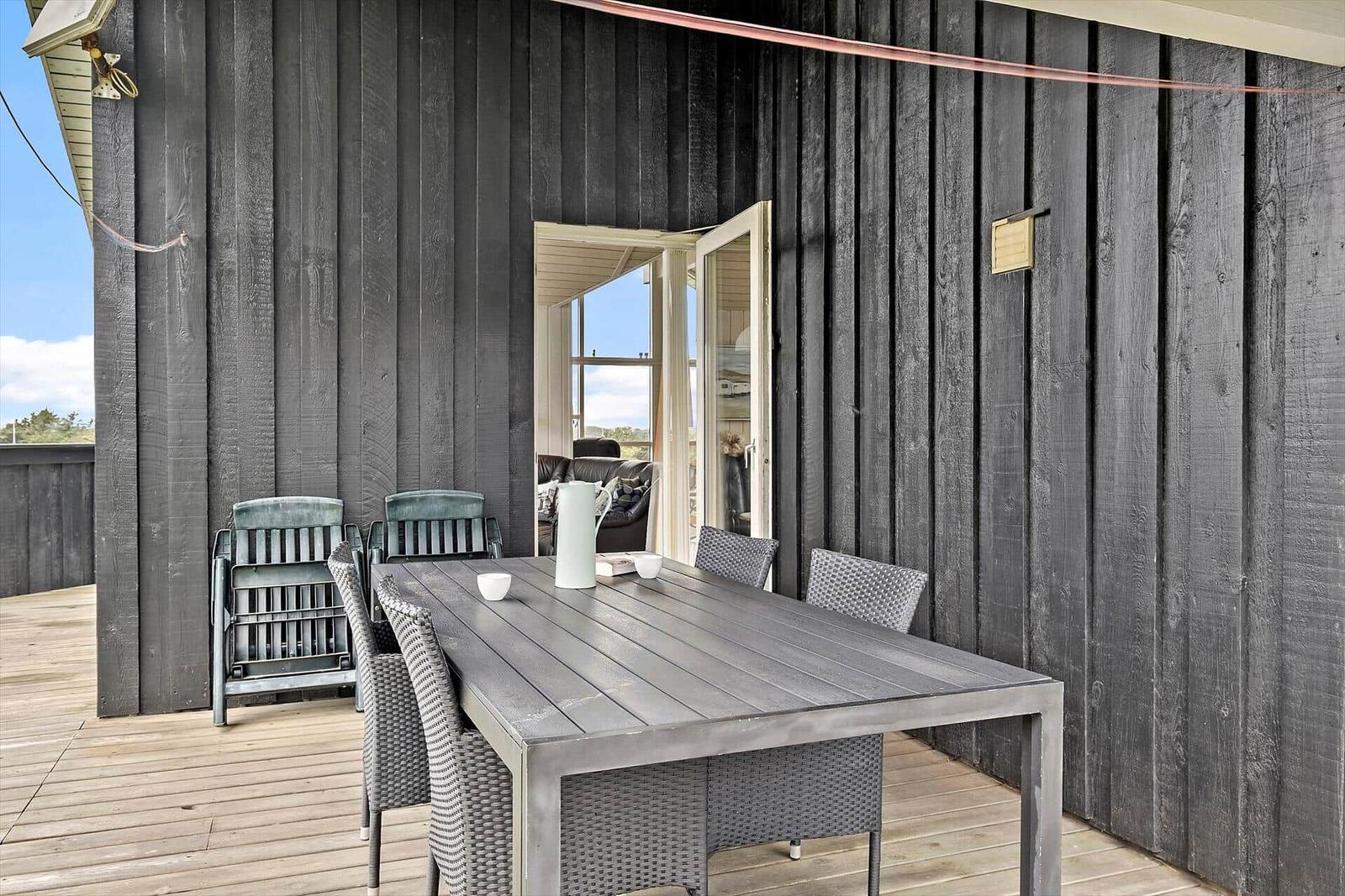 Terrasse mit Tisch und Stühlen, Tür führt ins Haus.