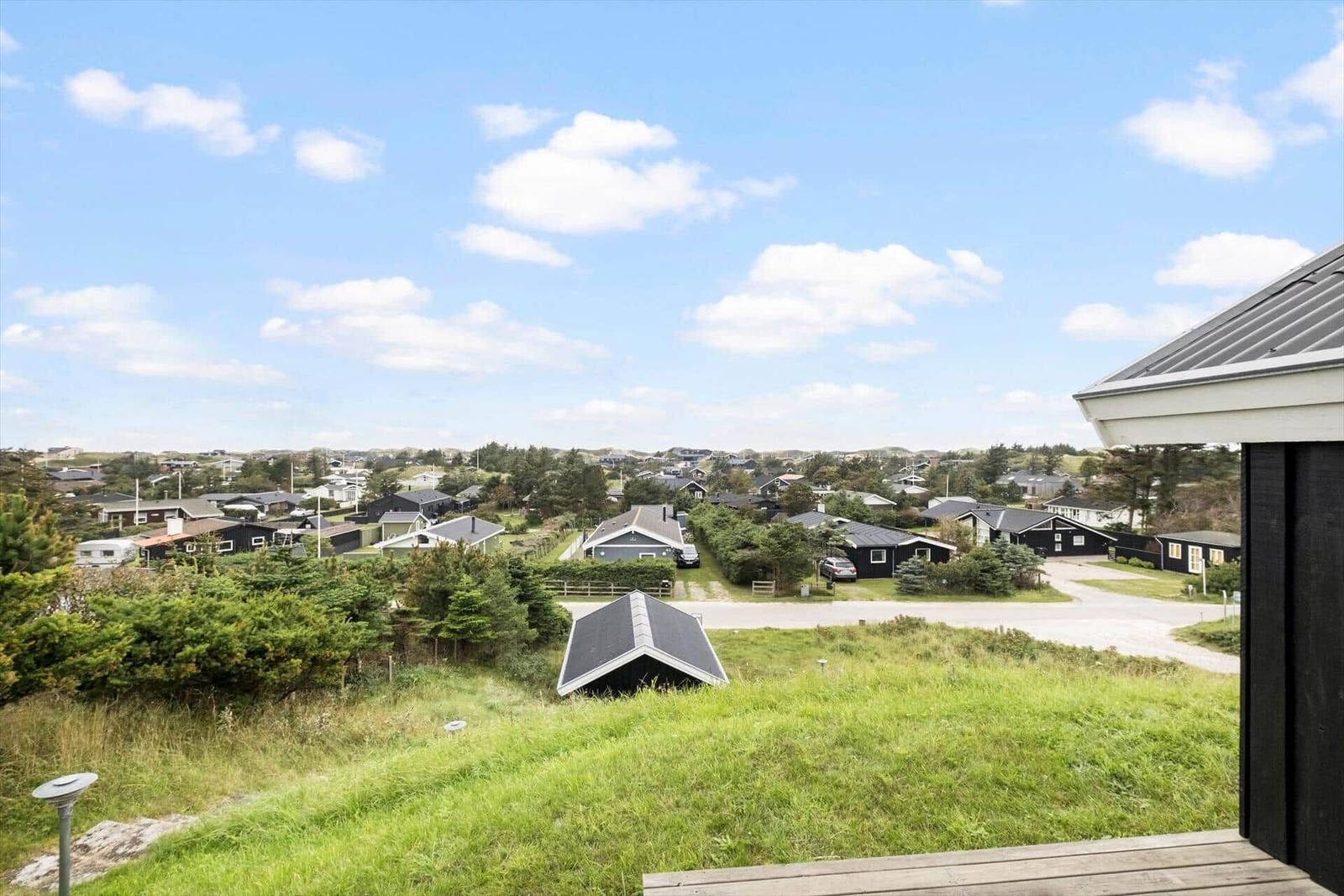 Weitläufiger Blick auf Wohngebiet mit Häusern und Grünflächen unter blauem Himmel.