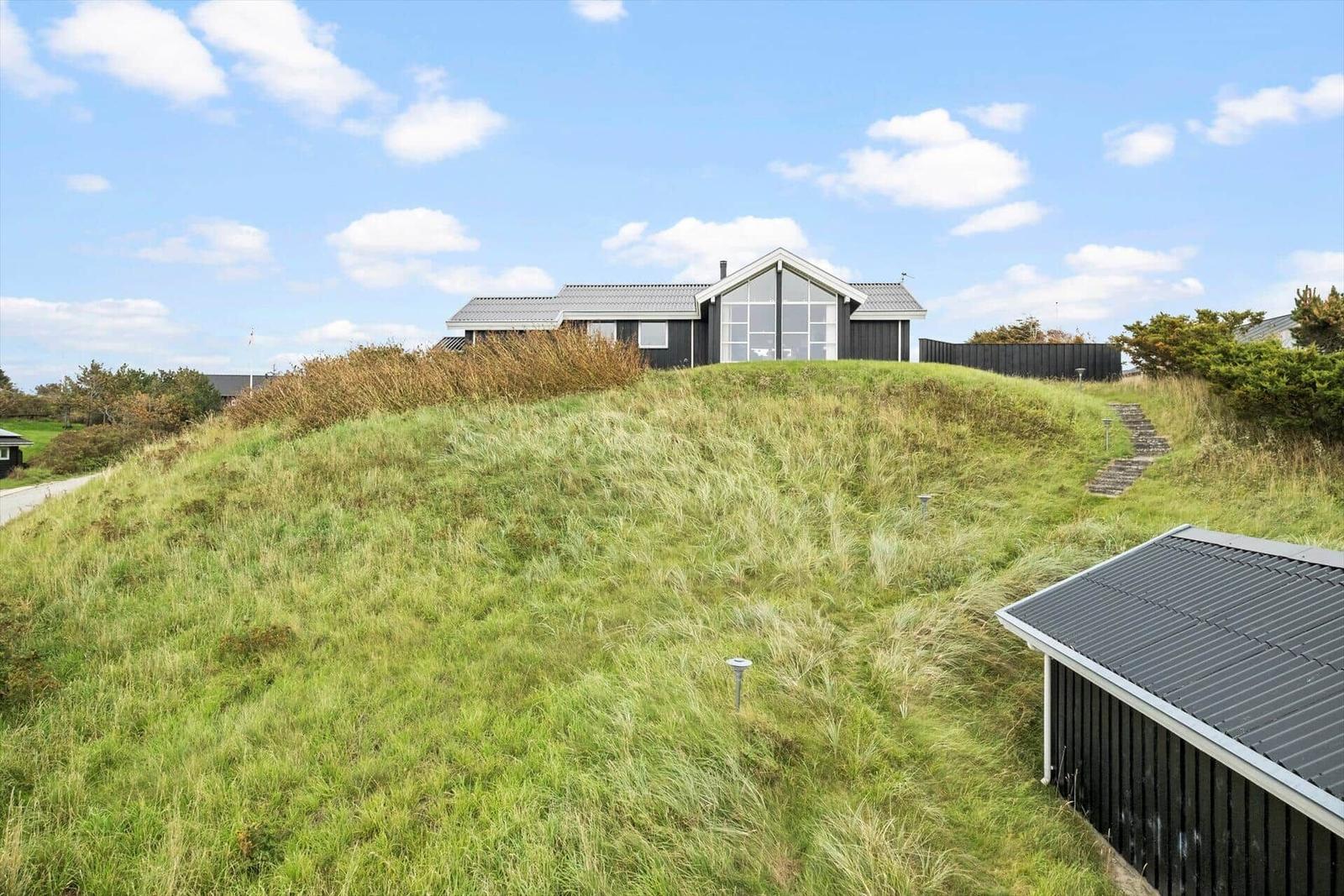 Moderne Villa auf grüner Anhöhe mit Blick auf den Himmel.