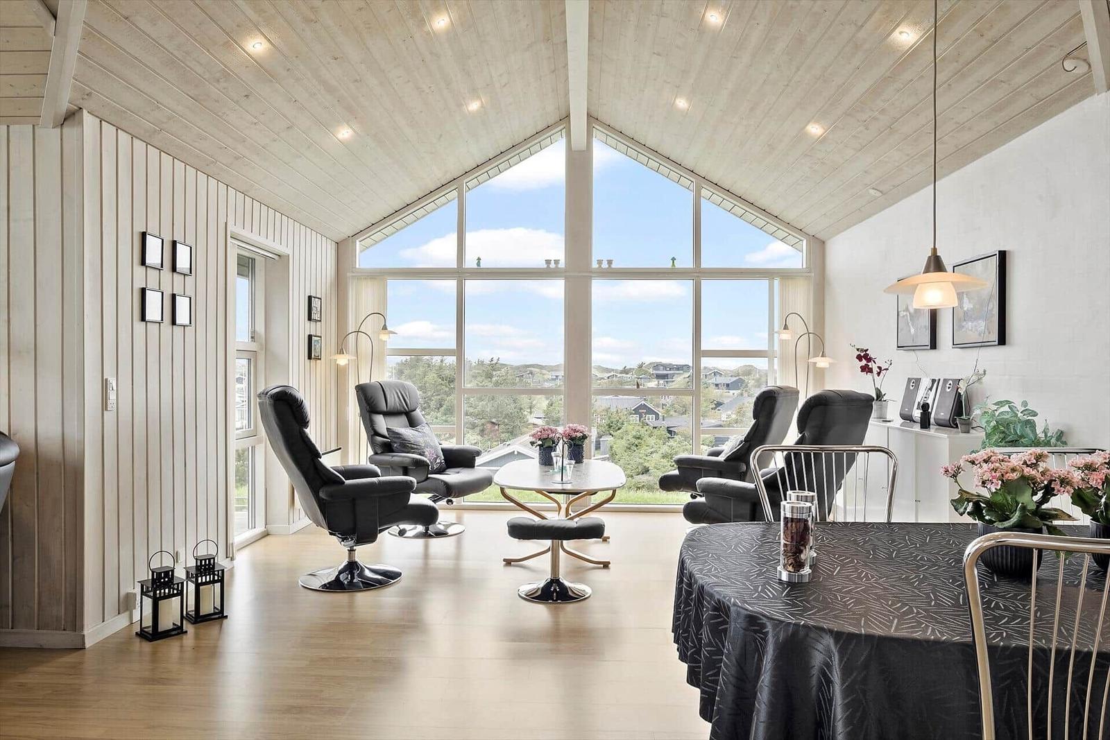 Großes Wohnzimmer mit Blick auf die Landschaft und schwarzen Sesseln.