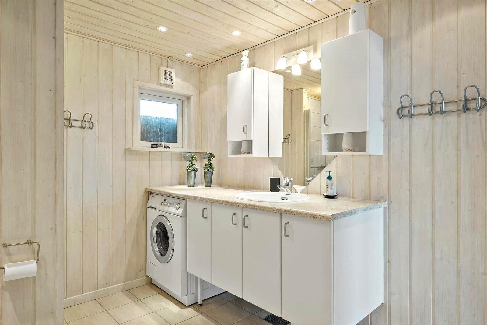 Badezimmer mit Waschmaschine, Spiegelschrank und Fenster.