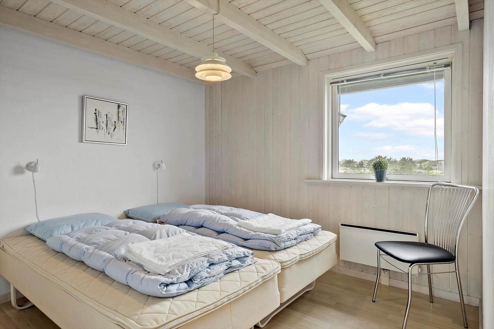 Schlafzimmer mit Doppelbett, Fenster und Stuhl