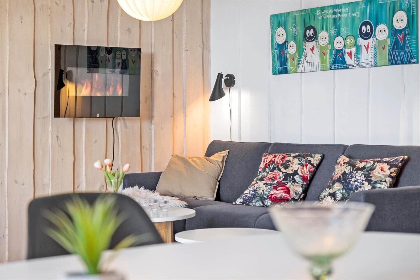 A living room with sofa, cushions, TV, and wall art.