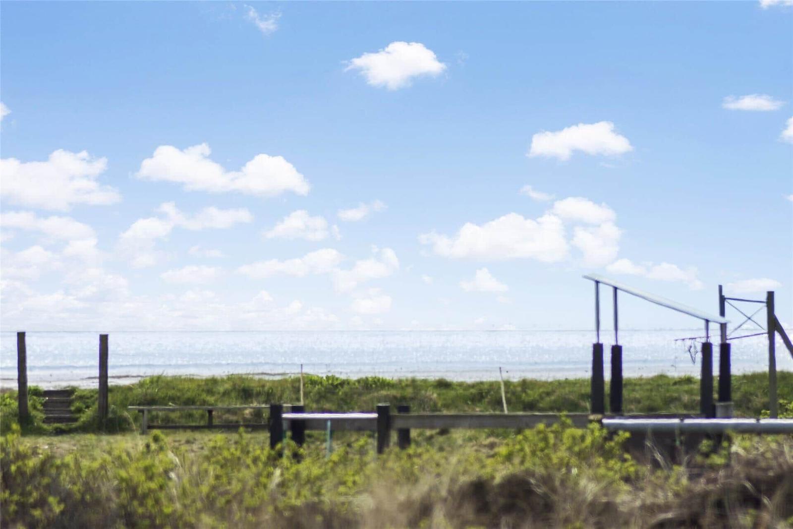Ocean in the background with grassland and wooden railing in the foreground.